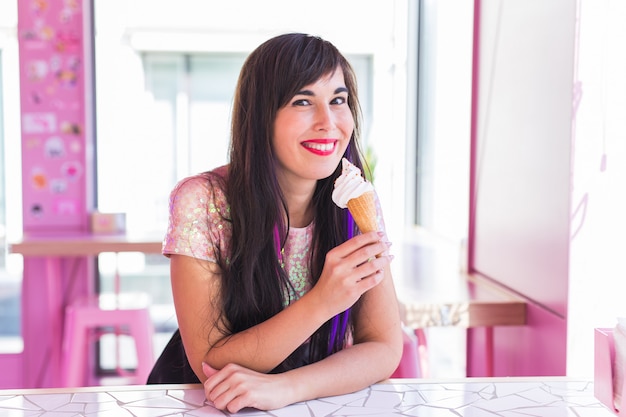 Concepto de verano, juventud y postre: niña bonita disfrutando de un helado en el café