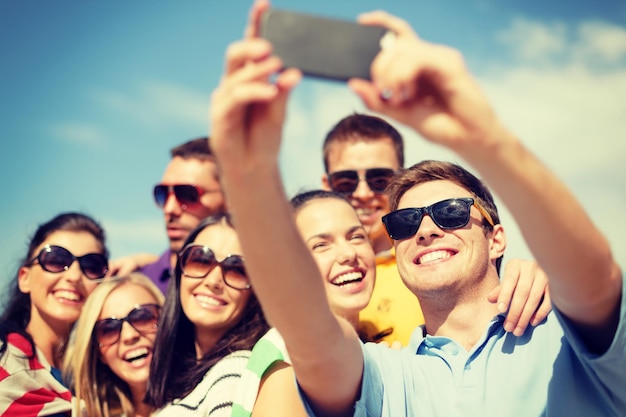 concepto de verano, vacaciones, vacaciones y felicidad - grupo de amigos tomando fotos con smartphone