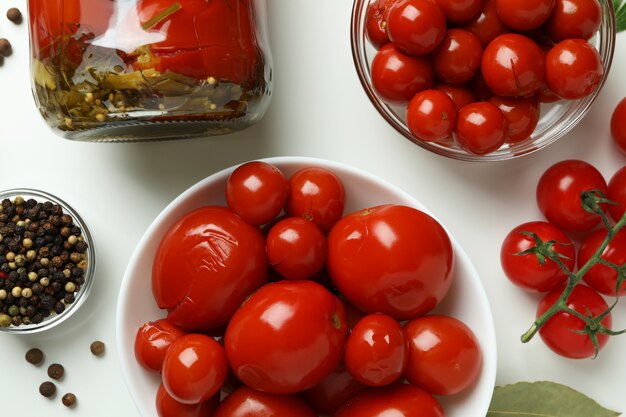 Concepto de verduras en escabeche con tomates en mesa blanca