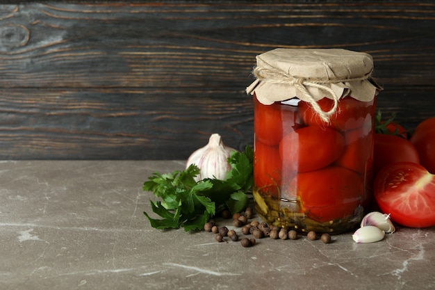 Concepto de verduras en escabeche con tomates en mesa con textura gris