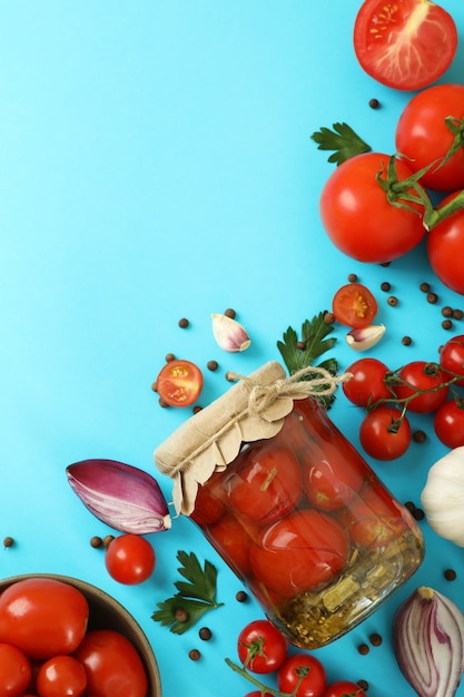 Concepto de verduras en escabeche con tomates sobre fondo azul.