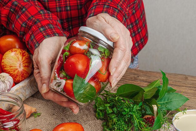 Concepto de verduras de temporada conservada Cosecha de tomate, chile, cebolla y ajo Las manos de la mujer preparan ingredientes para el proceso de cocción de alimentos enlatados Recetas saludables cocina casera espacio para copiar