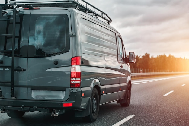 Concepto de viajar con una furgoneta y disfrutar de las aventuras al aire libre La furgonetta definitiva para acampar en Europa Furgoneta moderna para viajar con una escalera en la parte trasera y un soporte adicional para equipaje en el techo