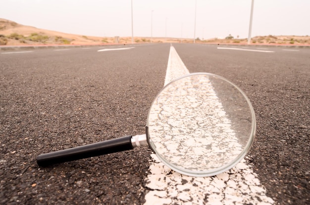 Concepto de viaje Ampliar lupa de vidrio en la carretera de Asphlat