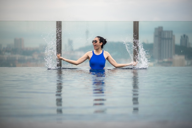 Concepto de viaje asiático. Mujer joven disfrutando de la vista del cielo de la ciudad desde la piscina de la azotea del hotel, estilo de vida de niña hermosa al aire libre en tiempo de vacaciones
