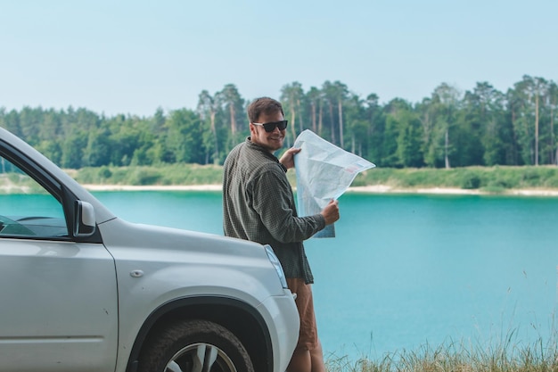 Concepto de viaje en automóvil hombre mirando al hombre en el lago del capó del automóvil suv en el fondo