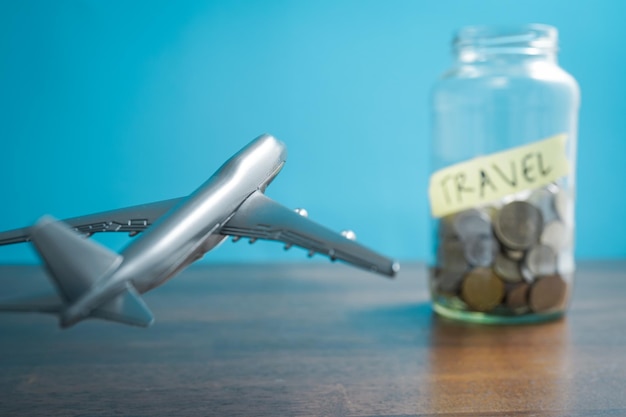 Concepto de viaje un avión en el aire en fondo azul imita volar con un frasco de monedas