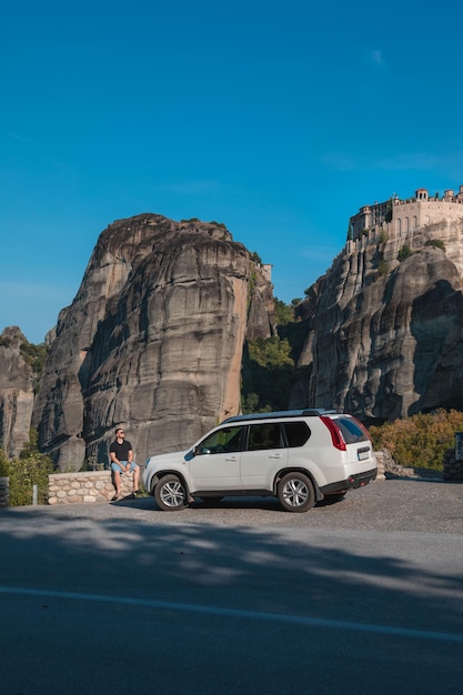 Concepto de viaje en coche de Grecia Hombre de pie cerca de suv mirando el monasterio de meteora montañas de tesalia