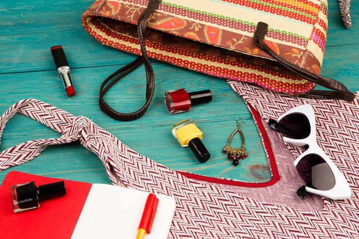 Foto concepto de viaje conjunto de cosas de mujer con accesorio de bloc de notas de bolsa de vestir y esmaltes de uñas sobre fondo de madera azul