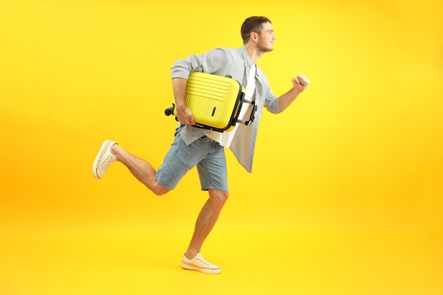 Foto concepto de viaje con joven feliz sobre fondo amarillo.