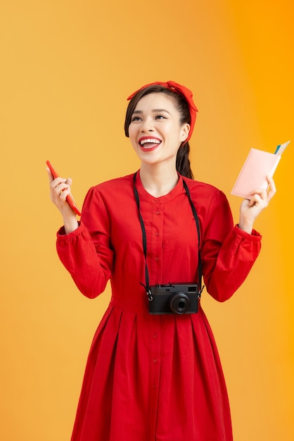 Foto concepto de viaje. joven turista asiática feliz con pasaporte con billetes de avión, aislado sobre fondo naranja