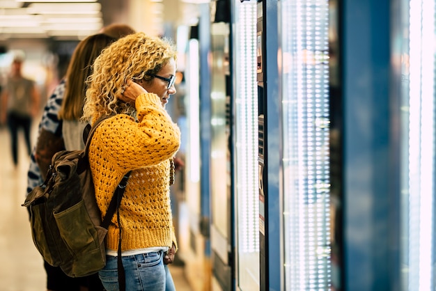 Concepto de viaje de mujer joven en la máquina de comida y bebida en el aeropuerto