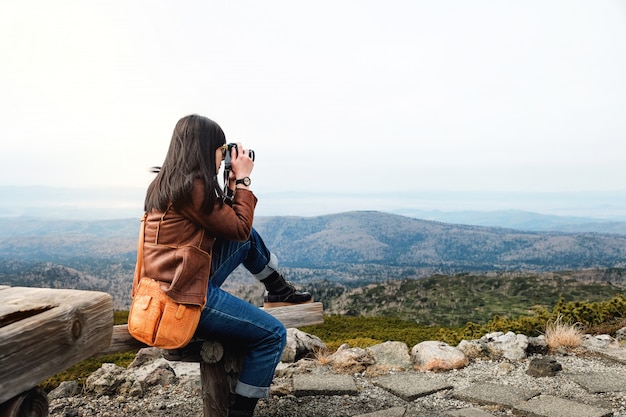 Concepto de viaje Mujer joven viajera con cámara tomando fotos en otoño