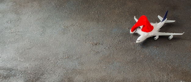 Concepto de viaje de Navidad o año nuevo. Avión de juguete y sombrero de Santa Claus. Navidad viajando baner.