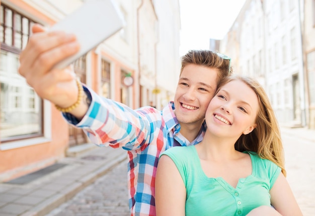 concepto de viaje, vacaciones, tecnología y amistad - pareja sonriente con smartphone en la ciudad