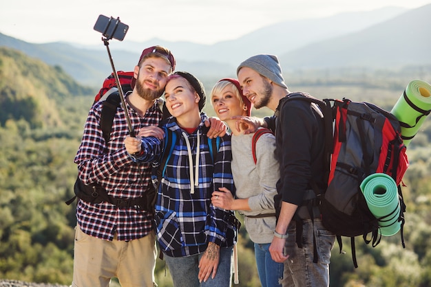 Foto concepto de viaje de verano. amigos felices que usan el mapa de papel cerca del coche alquilado en la naturaleza.