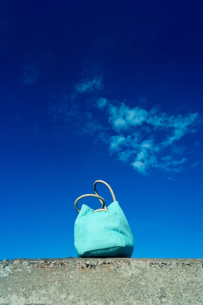 Concepto de viaje de verano. Bolsa de playa azul y fondo de cielo azul