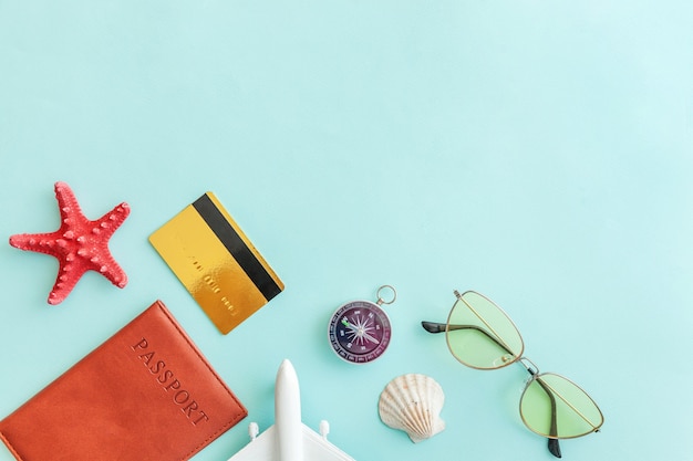 concepto de viaje de viaje de vacaciones. Pasaporte de avión gafas de sol brújula tarjeta de crédito dorada sobre fondo azul.