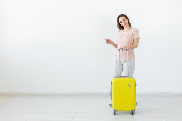 Concepto de viaje, viajes y vacaciones - mujer con su maleta amarilla en el espacio de copia