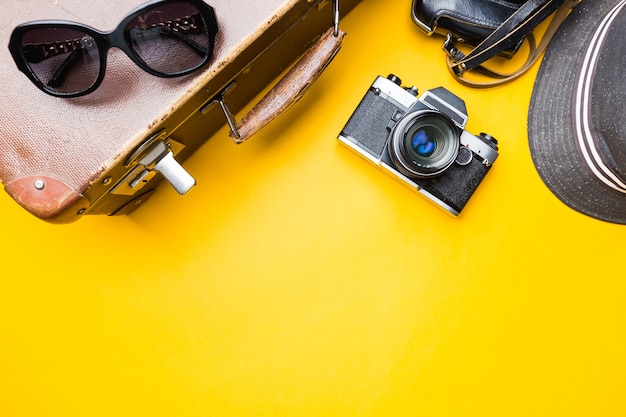 Concepto de viaje de vista superior con películas de cámara retro, maleta, gafas de sol y sombrero en amarillo con espacio de copia