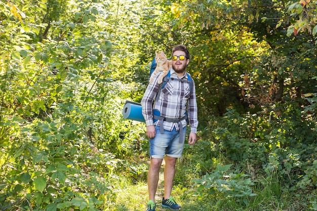 Concepto de viajes, aventuras, caminatas, turismo y naturaleza - Turista con gato caminando en el bosque.