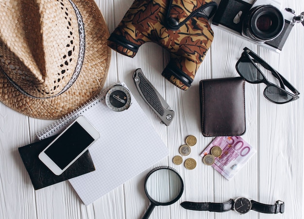 Foto concepto de viajes, documentos, sombrero, brújula, dinero, teléfono y cámara sobre un fondo blanco