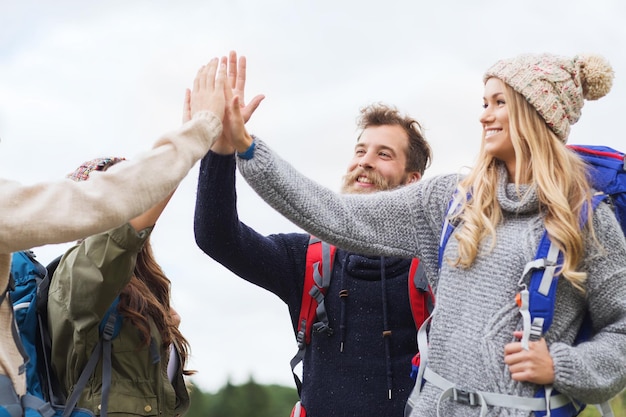 concepto de viajes, turismo, caminatas, gestos y personas - grupo de amigos sonrientes con mochilas haciendo cinco al aire libre