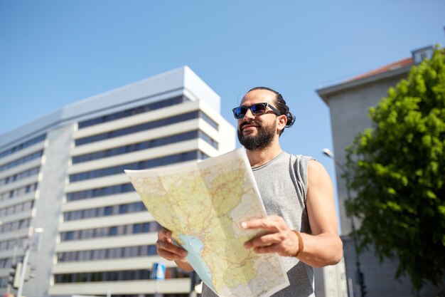Foto concepto de viajes, turismo, mochileros y personas - hombre que viaja con mochila y mapa en la ciudad buscando ubicación