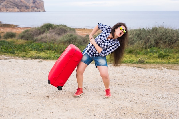 Concepto de viajes, turismo y personas - mujer joven emocional feliz que va a viajar en coche con dos maletas enormes.