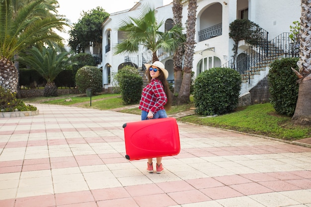 Concepto de viajes, turismo y personas. mujer joven feliz que va a viajar con maleta roja y sonriendo.