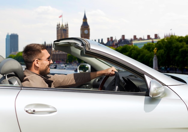 concepto de viajes, turismo, transporte, ocio y personas - hombre feliz cerca de un camión cabriolet sobre el fondo de la ciudad de Londres