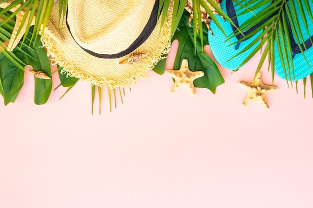 Concepto de viajes y vacaciones de verano Hojas de palma sombrero de conchas marinas y chanclas sobre fondo rosa Plano con espacio para copiar