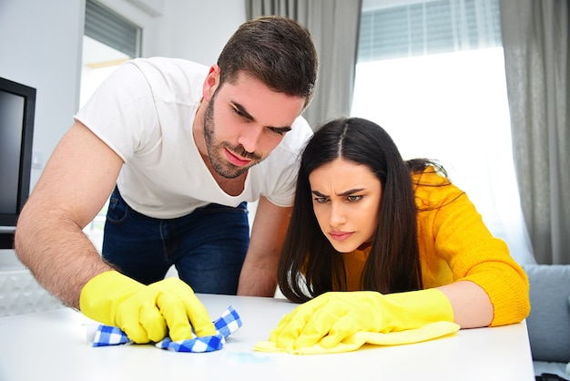 Concepto de vida matrimonial, parejas, limpieza, trabajos domésticos y deberes. Joven y mujer limpiando y limpiando la casa juntos.e