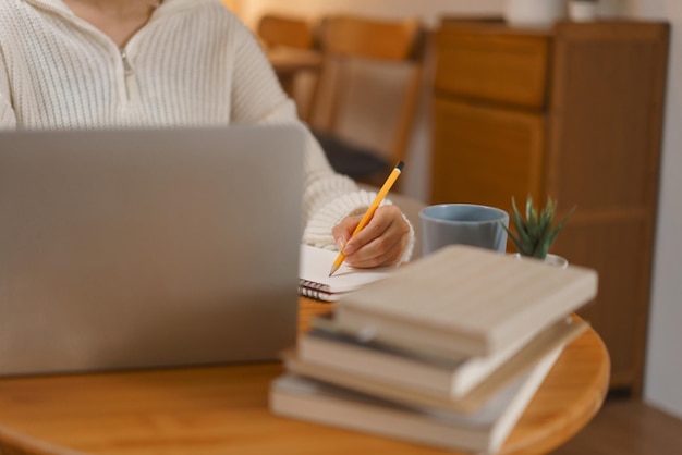 Concepto de vida nocturna Mujer joven que trabaja en una computadora portátil y escribe datos en un cuaderno a altas horas de la noche de invierno