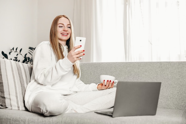 Concepto de videollamadas. Chica joven estudiante sonriendo y teniendo videollamada a través de la computadora portátil en casa