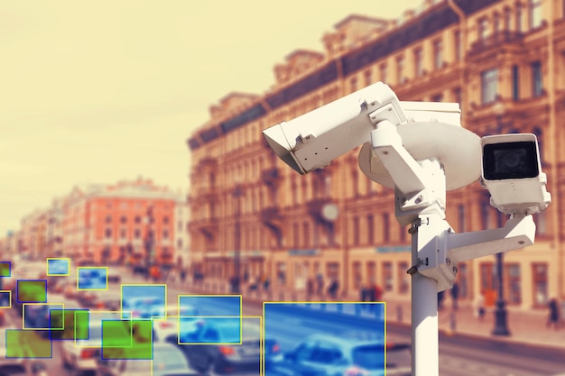 El concepto de videovigilancia y tecnologías de seguridad. Cámara de videovigilancia en el fondo de la carretera de la ciudad con coches. Zona de definición.