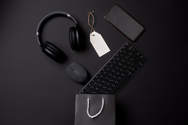 Foto concepto de viernes negro una bolsa de compras con auriculares de ratón de teclado de computadora y teléfono móvil