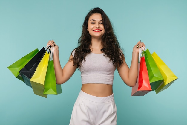 Concepto de viernes negro. Niña feliz tiene bolsas de compras sobre fondo azul.