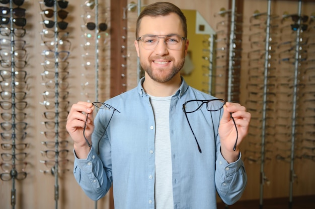 Concepto de vista y visión de atención médica Hombre feliz eligiendo anteojos en el enfoque selectivo de la tienda de óptica