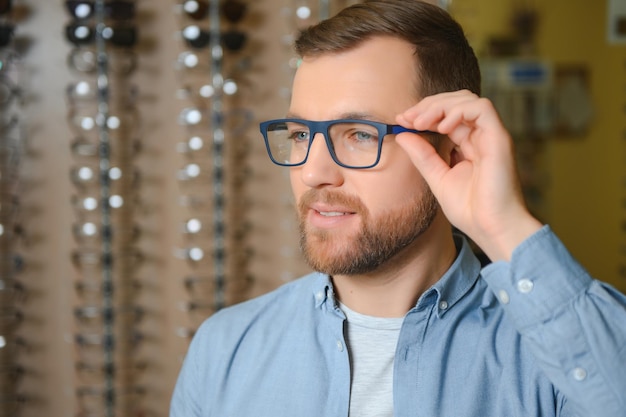 Concepto de vista y visión de atención médica Hombre feliz eligiendo anteojos en el enfoque selectivo de la tienda de óptica