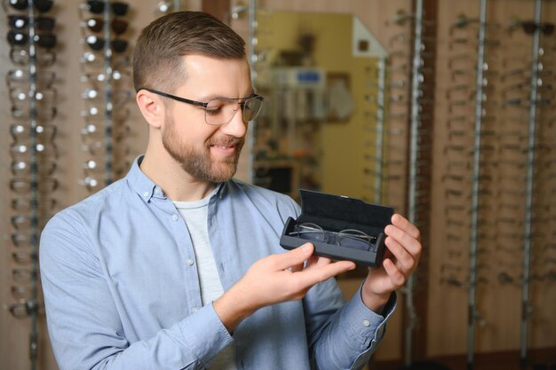 Concepto de vista y visión de atención médica Hombre feliz eligiendo anteojos en el enfoque selectivo de la tienda de óptica