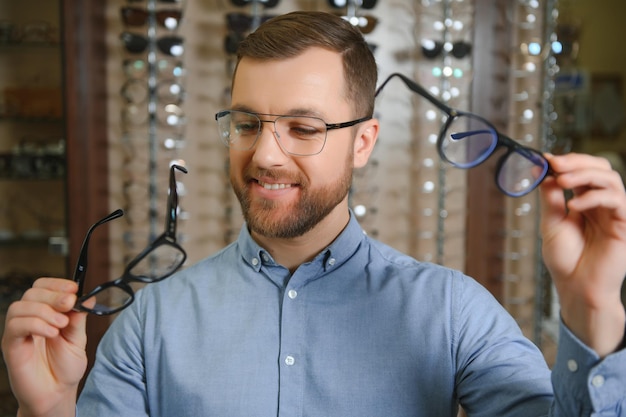 Concepto de vista y visión de atención médica Hombre feliz eligiendo anteojos en el enfoque selectivo de la tienda de óptica