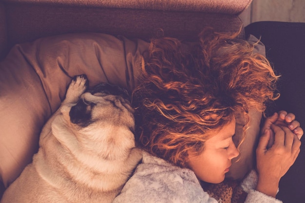 Conceptos de amistad para mujeres de 40 años durmiendo con su mejor perro pug de amigos en casa Tanto en la almohada como en tonos marrones cálidos Soñando juntos Estado de ánimo de imagen de amor y amistad