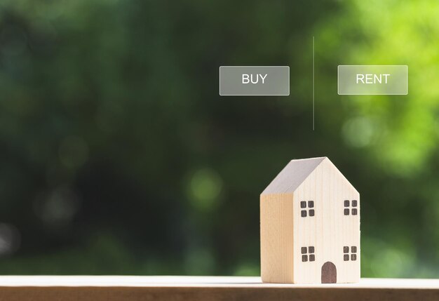 Conceptos inmobiliarios Modelo de casa de madera en miniatura con opción de propiedad de compra o alquiler fondo verde borroso Casa ecológica en entorno verde