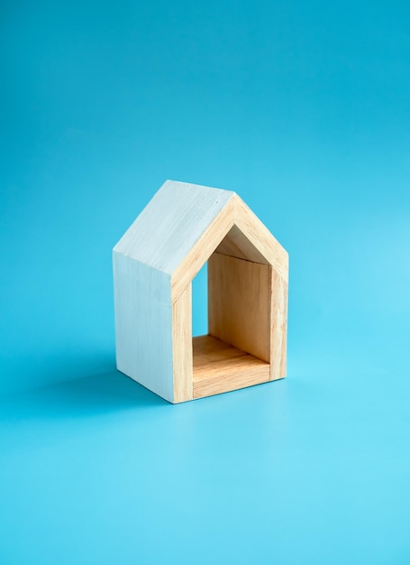 Conceptos de propiedad inmobiliaria de la familia de la casa Casa pequeña de madera blanca de madera en miniatura mínima con área vacía dentro para texto o logotipo aislado en estilo vertical de fondo azul