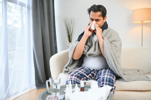 Foto conceptos de salud y gente enfermo joven indio con manta con dolor de cabeza o fiebre en casa