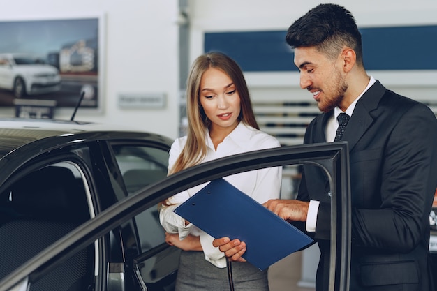 Concesionario de automóviles hombre mostrando a una mujer comprador un coche nuevo