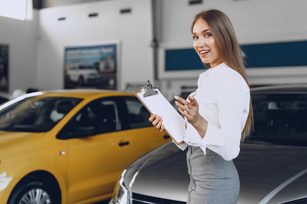 Concesionario de coches joven hermosa feliz en la sala de exposición de cerca