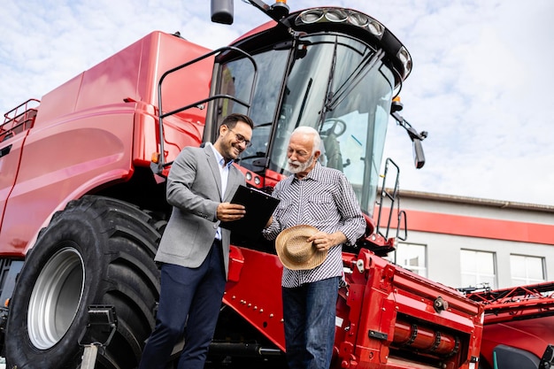 Foto concesionario de tractores y agricultor negociando la compra de una cosechadora