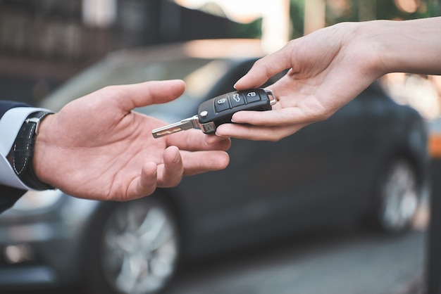 Concessionária de automóveis jovem recebendo a chave do carro da vendedora